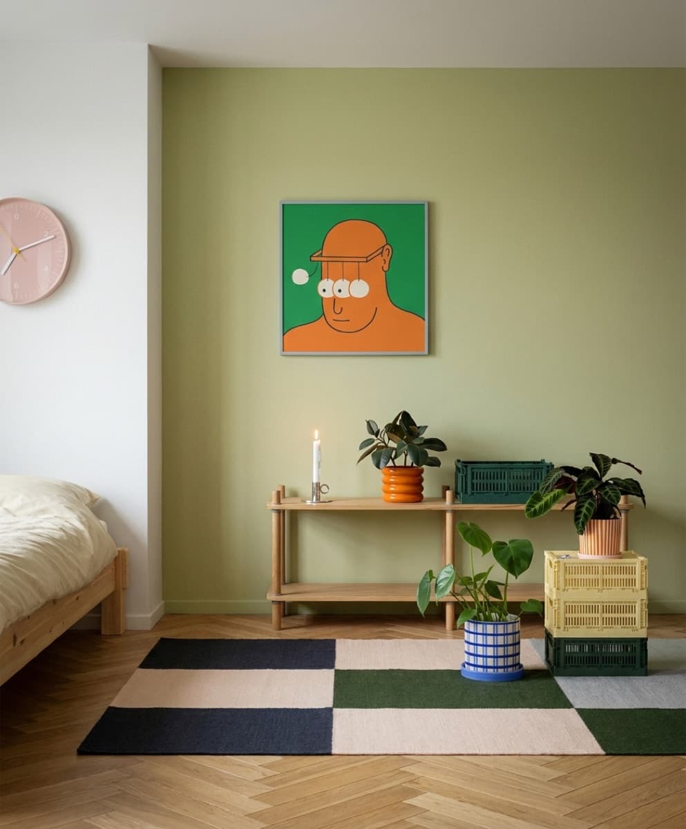 Ett innrammet kunsttrykk i et rolig, grønntonet skandinavisk soverom