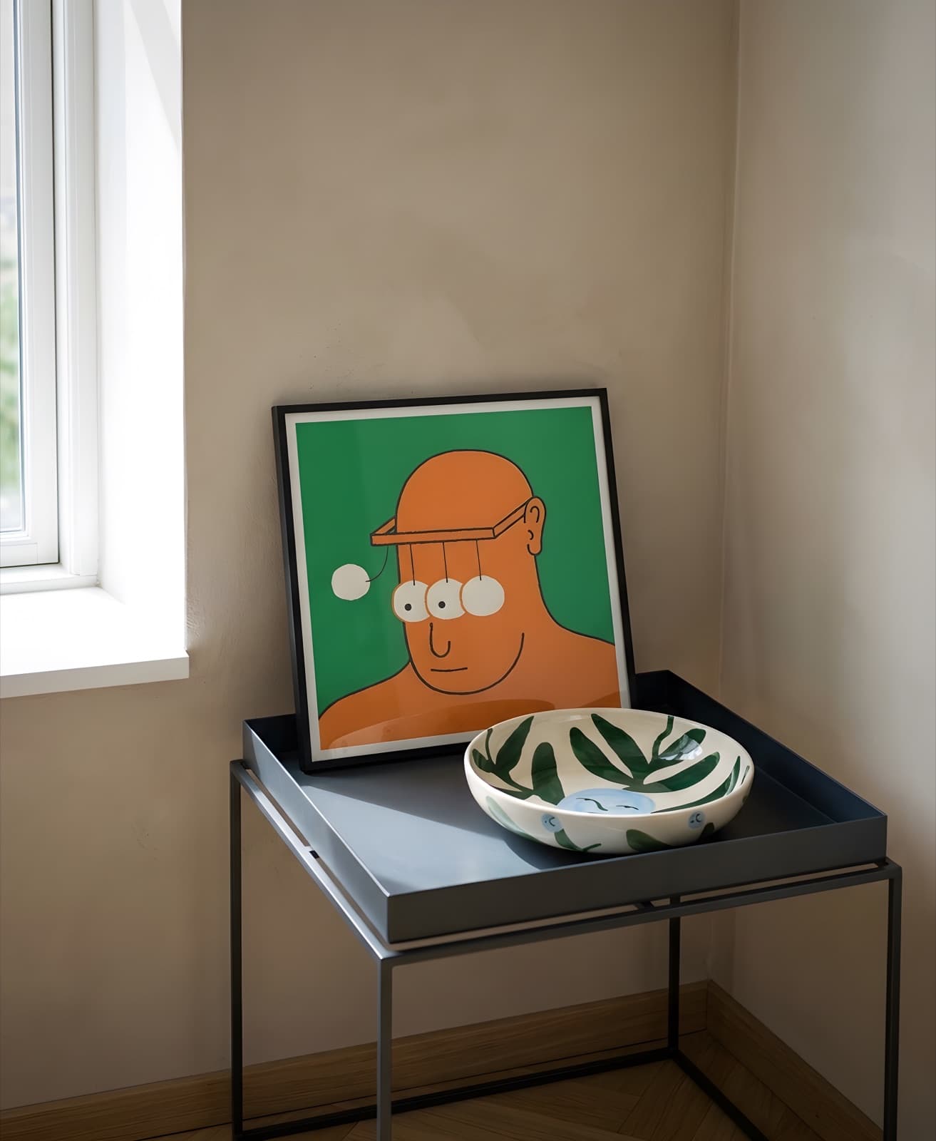Mean Snothing framed on a grey tray table with a patterned ceramic bowl