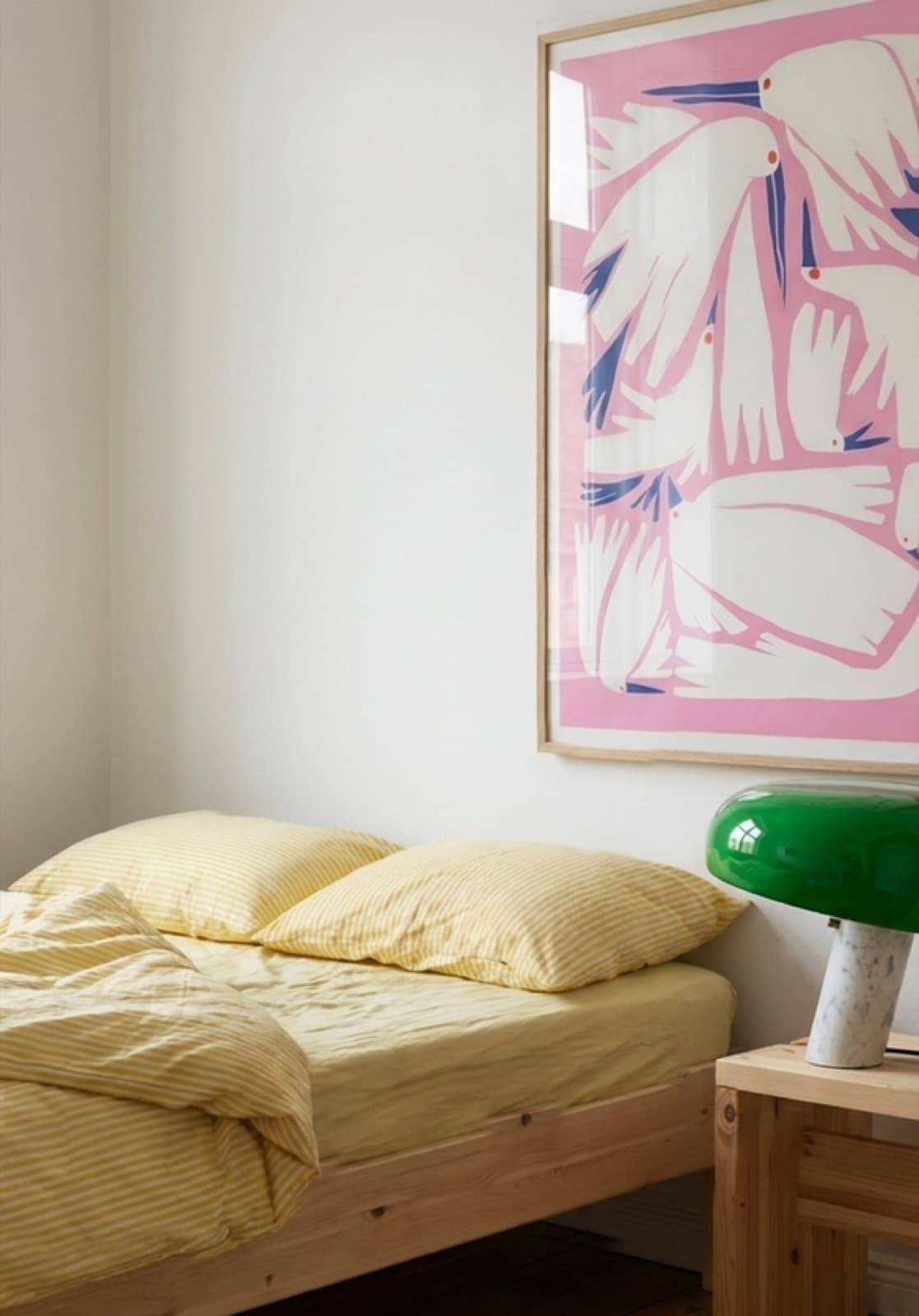 Birdie Pink above a bed with yellow striped bedding and a green glass lamp