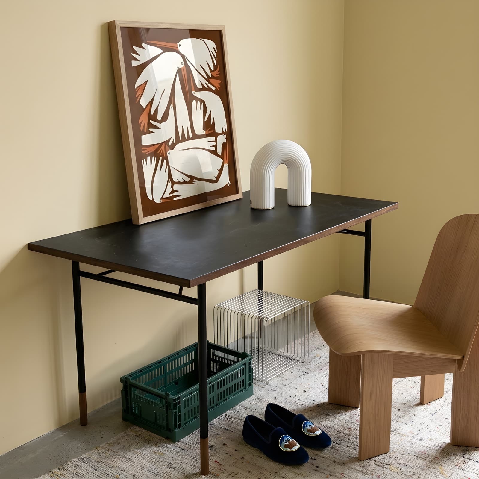 Birdie Brown leaning on a dark desk beside a white ribbed vase