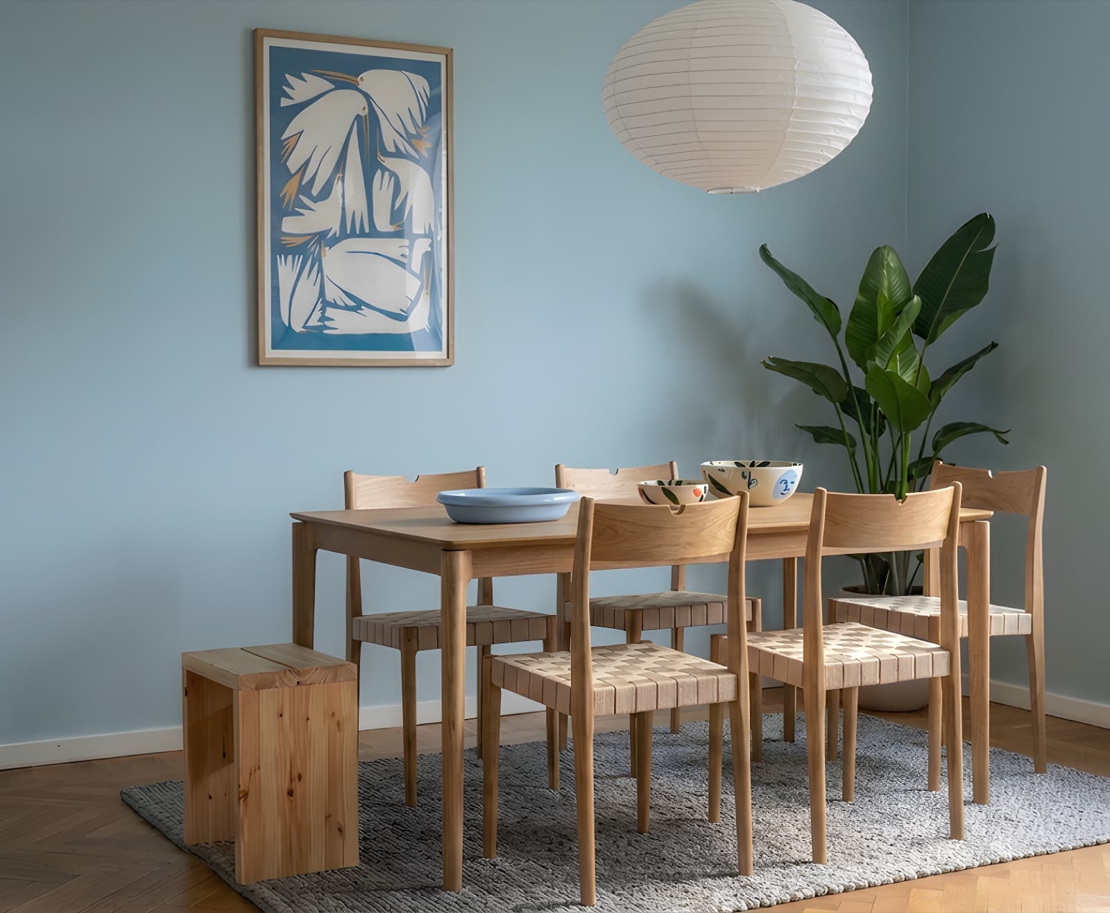 Birdie Blue over a light wood dining table in a soft blue room