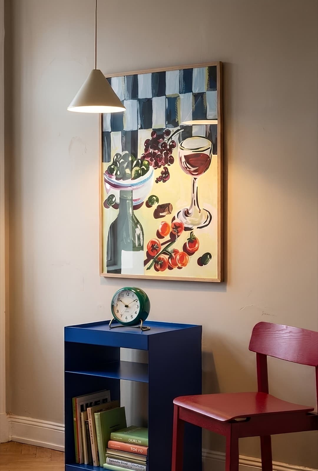 Vinkveld above a cobalt side table and an oxblood chair, lit by a cone pendant